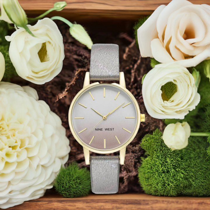 Classic ladies' watch with elegant gold-toned design, surrounded by beautiful white flowers and lush greenery on a wooden background.