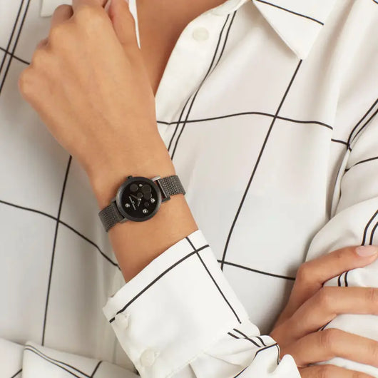 Ladies' black stainless steel watch with modern geometric pattern on white blouse