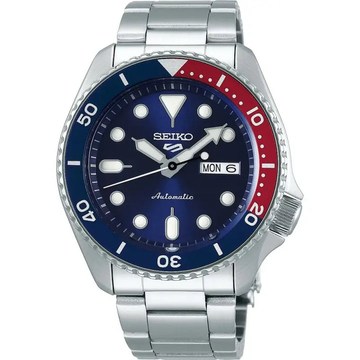 Stainless steel men's automatic Seiko watch with a navy blue and red bezel, displaying the day and date functions.