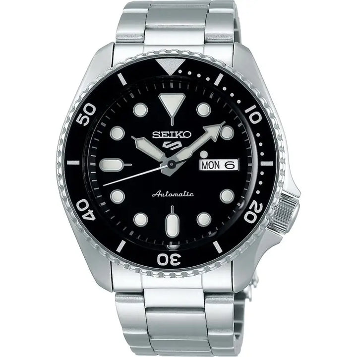 Stainless steel men's watch with black dial and silver-tone metal bracelet. The watch features a day-date display, automatic movement, and a rotating bezel for timing functions. The Seiko brand logo is prominently displayed at the center of the dial.